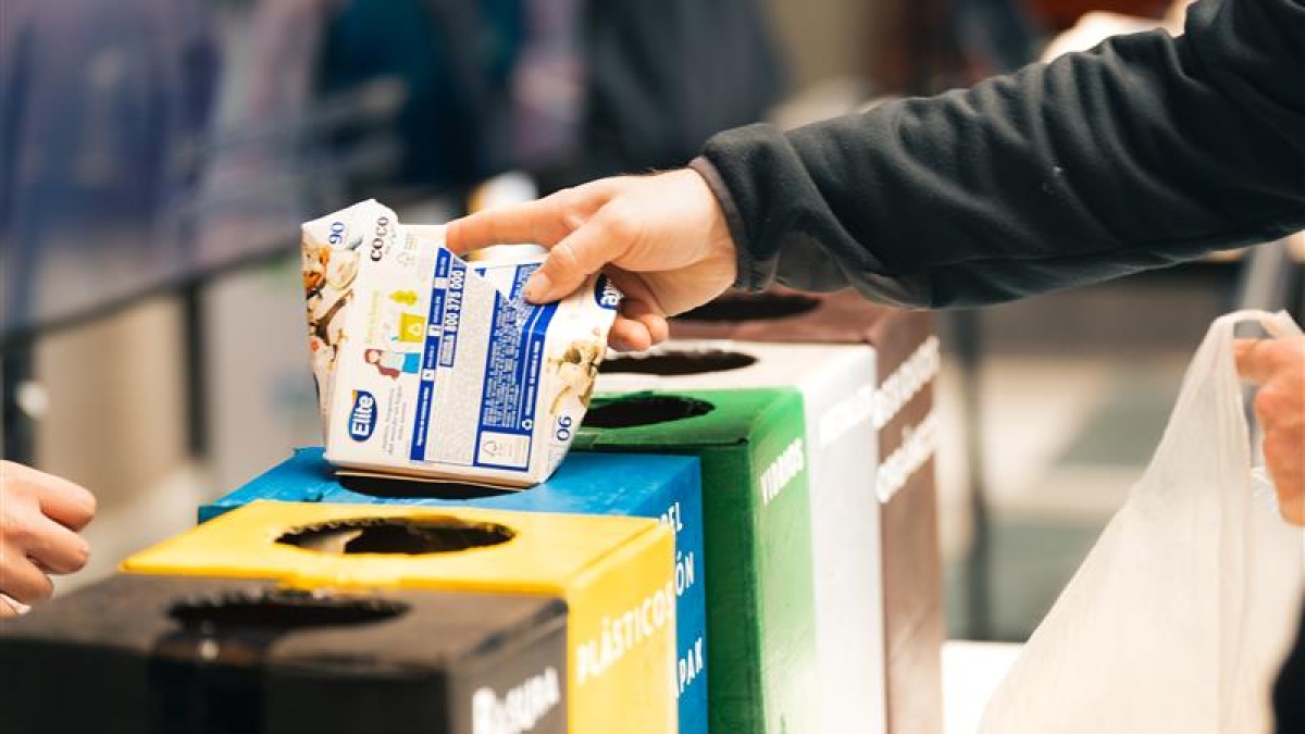 Persona reciclando y separando residuos por contenedor